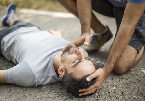 Man gives first aid to a person on the asphalt